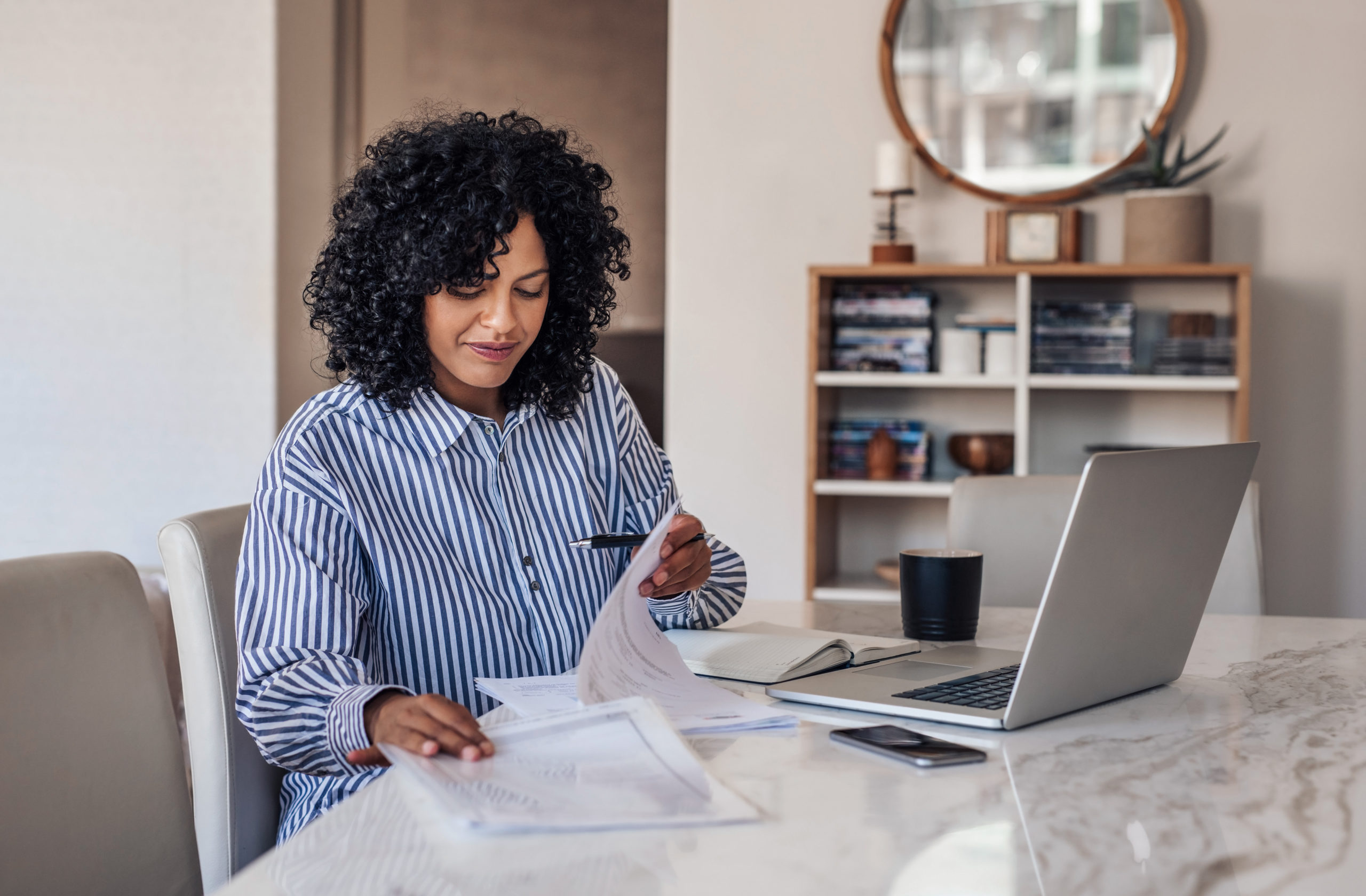 Woman sits at kitchen counter and researches foster care agencies.