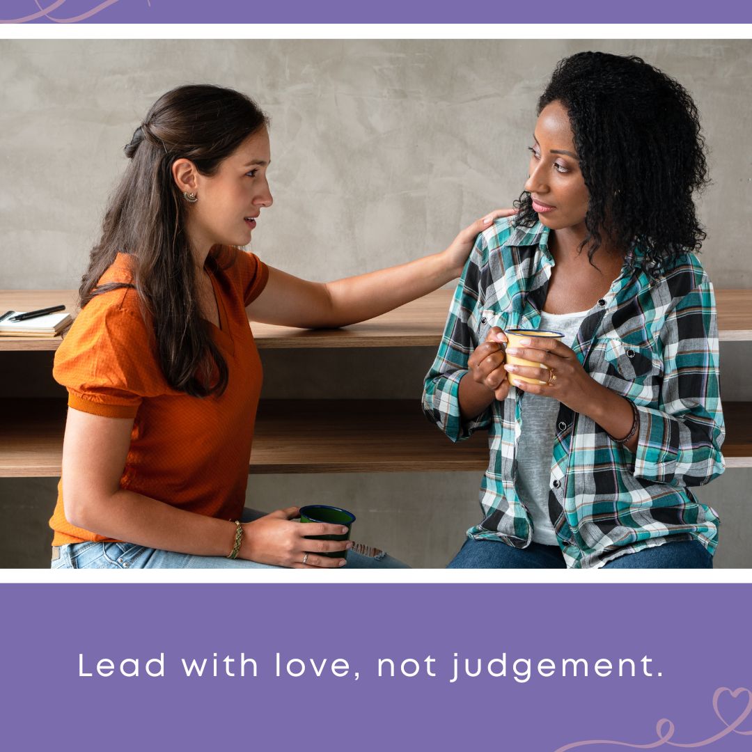 Two women sit together over coffee, one placing a gentle hand on the other's shoulder in a moment of compassionate listening. Text overlay reads: "Lead with love, not judgement."