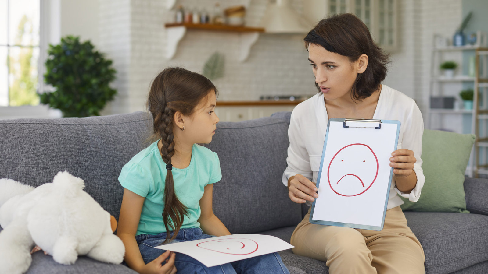 Counselor speaks with a child on a couch.