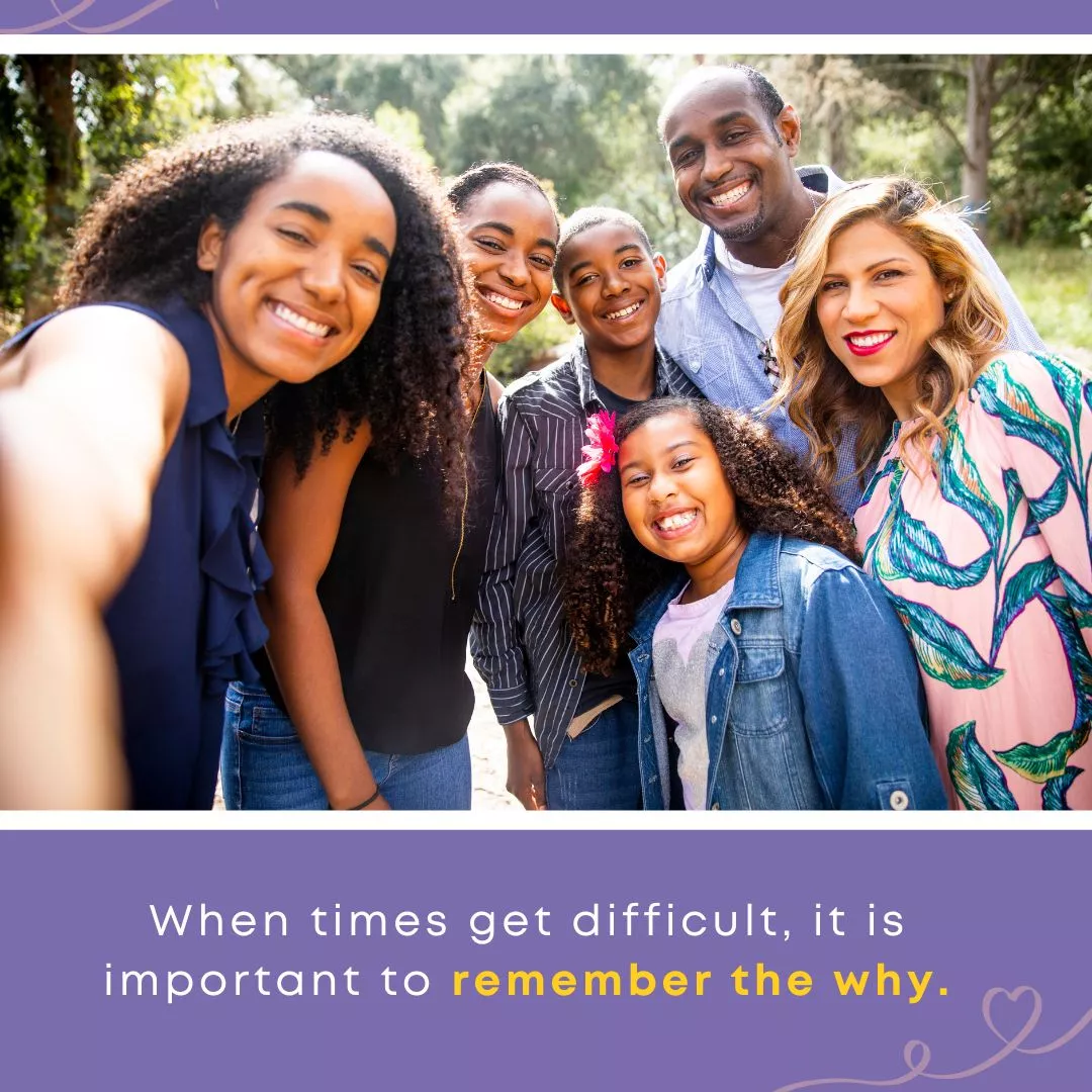 A joyful, diverse family of six smiles together outdoors, taking a selfie surrounded by greenery. Text overlay reads: "When times get difficult, it is important to remember the why."