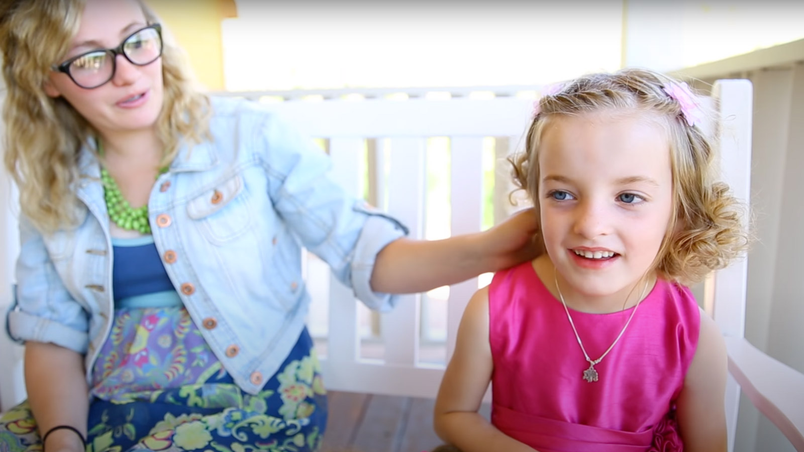 Mom and adopted daughter sit on a porch screen.